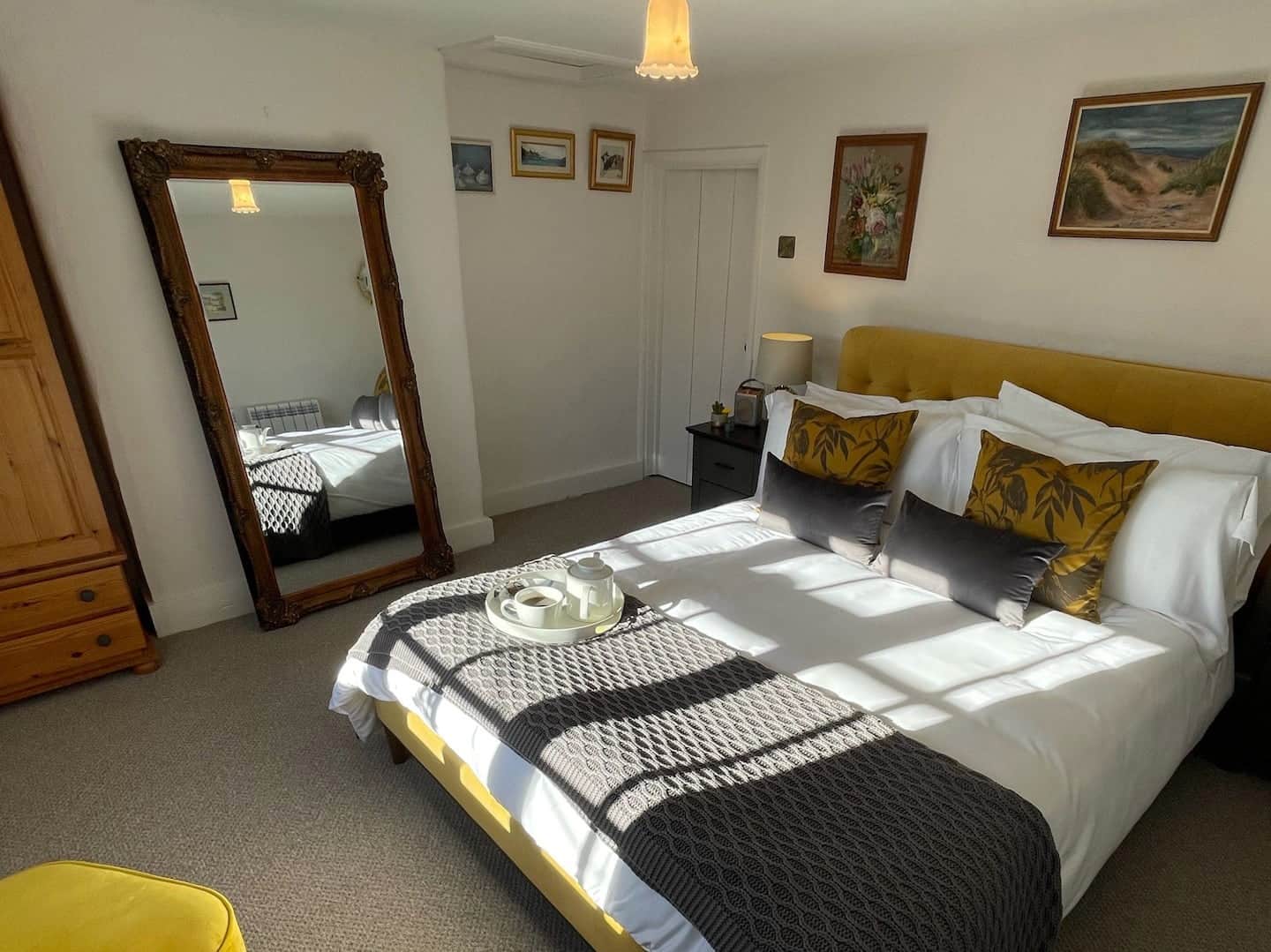 Bedroom with a sumptuous king size bed, large gilt mirror and crisp white linens